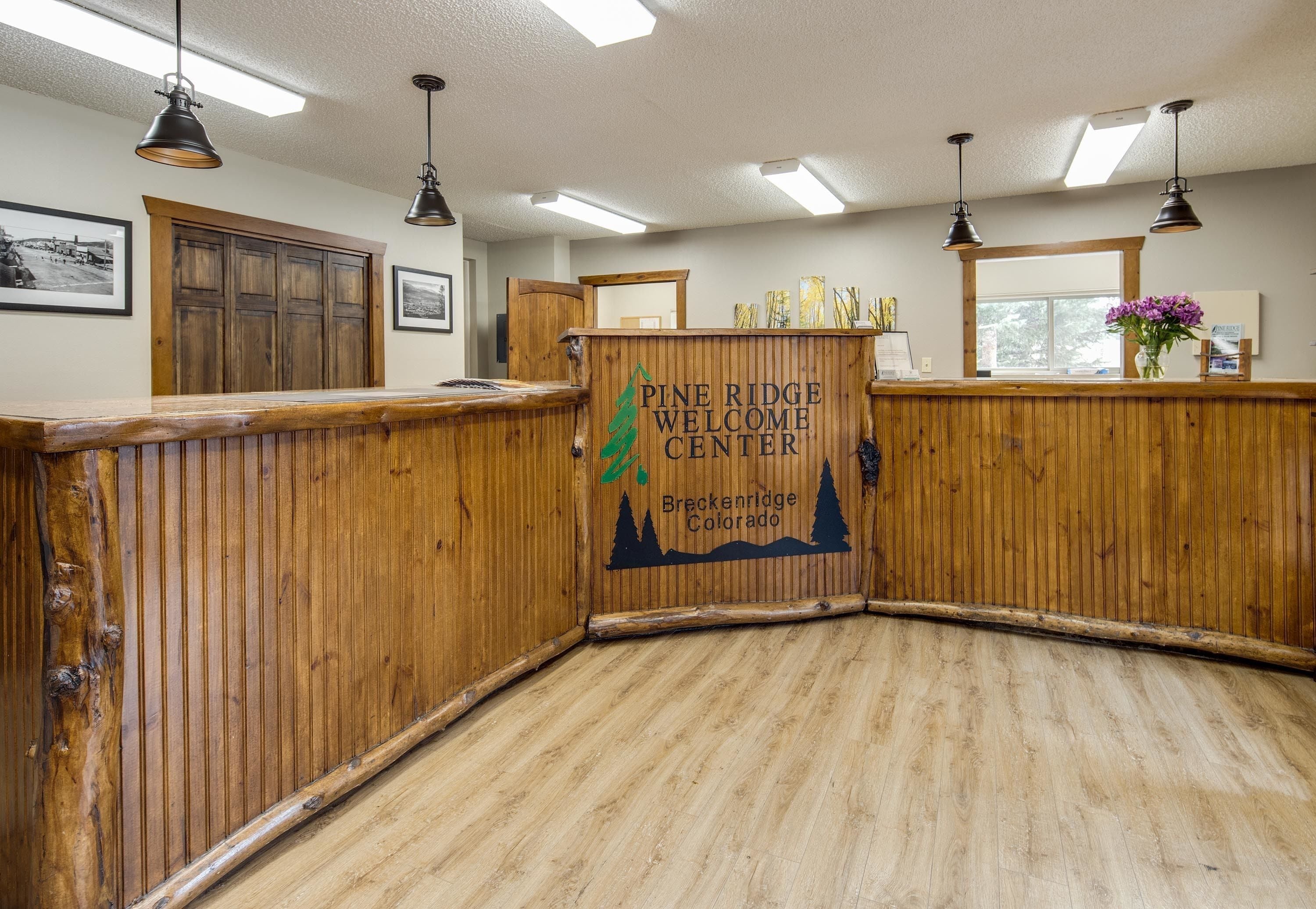 Centro de bienvenida de Pine Ridge con paneles de madera, un mostrador de recepción y una ventana con vistas a árboles.
