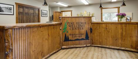 Centro de bienvenida de Pine Ridge con paneles de madera, un mostrador de recepción y una ventana con vistas a árboles.