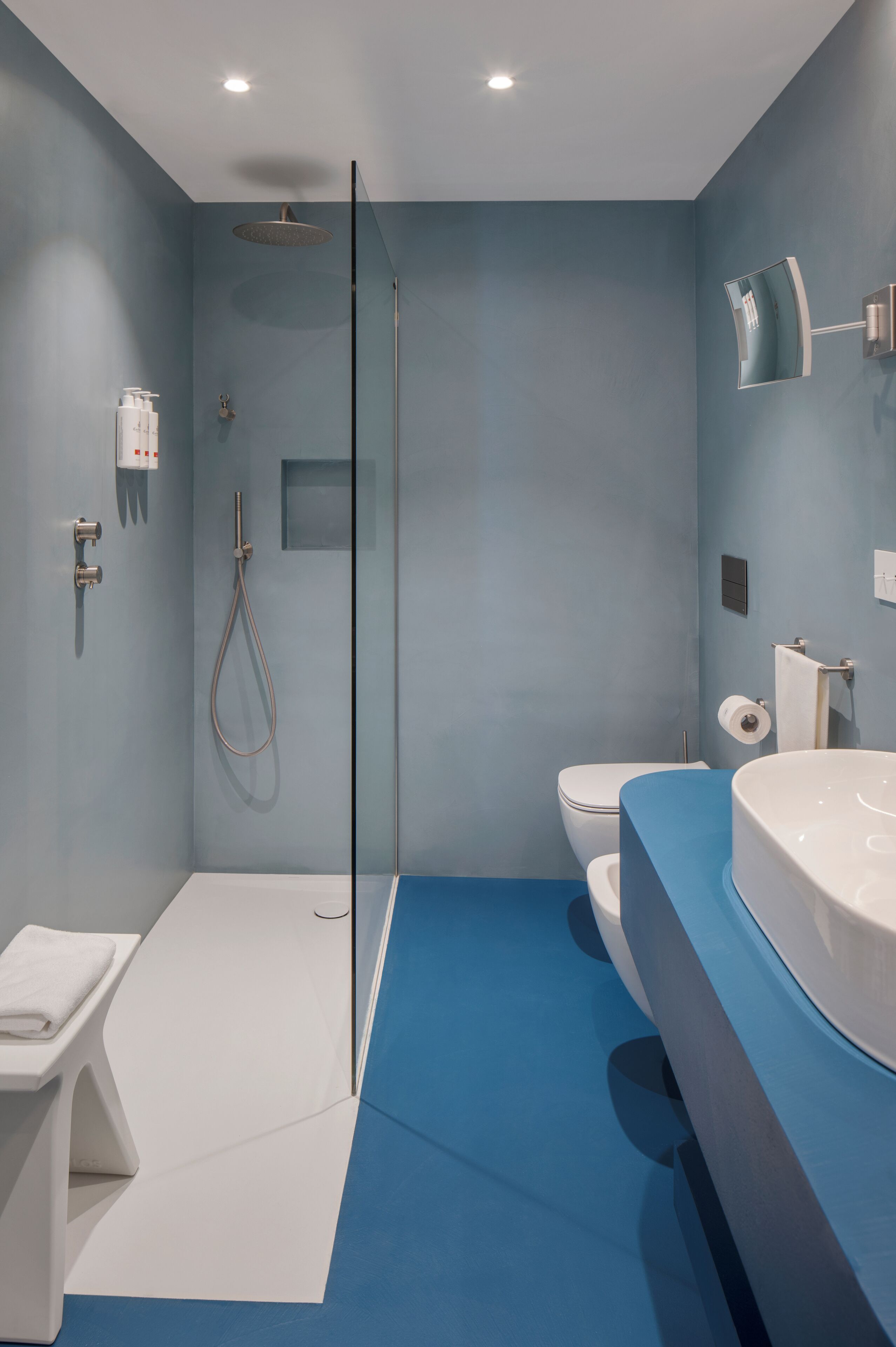 A modern bathroom with a glass shower enclosure, a white toilet, and a large white sink.