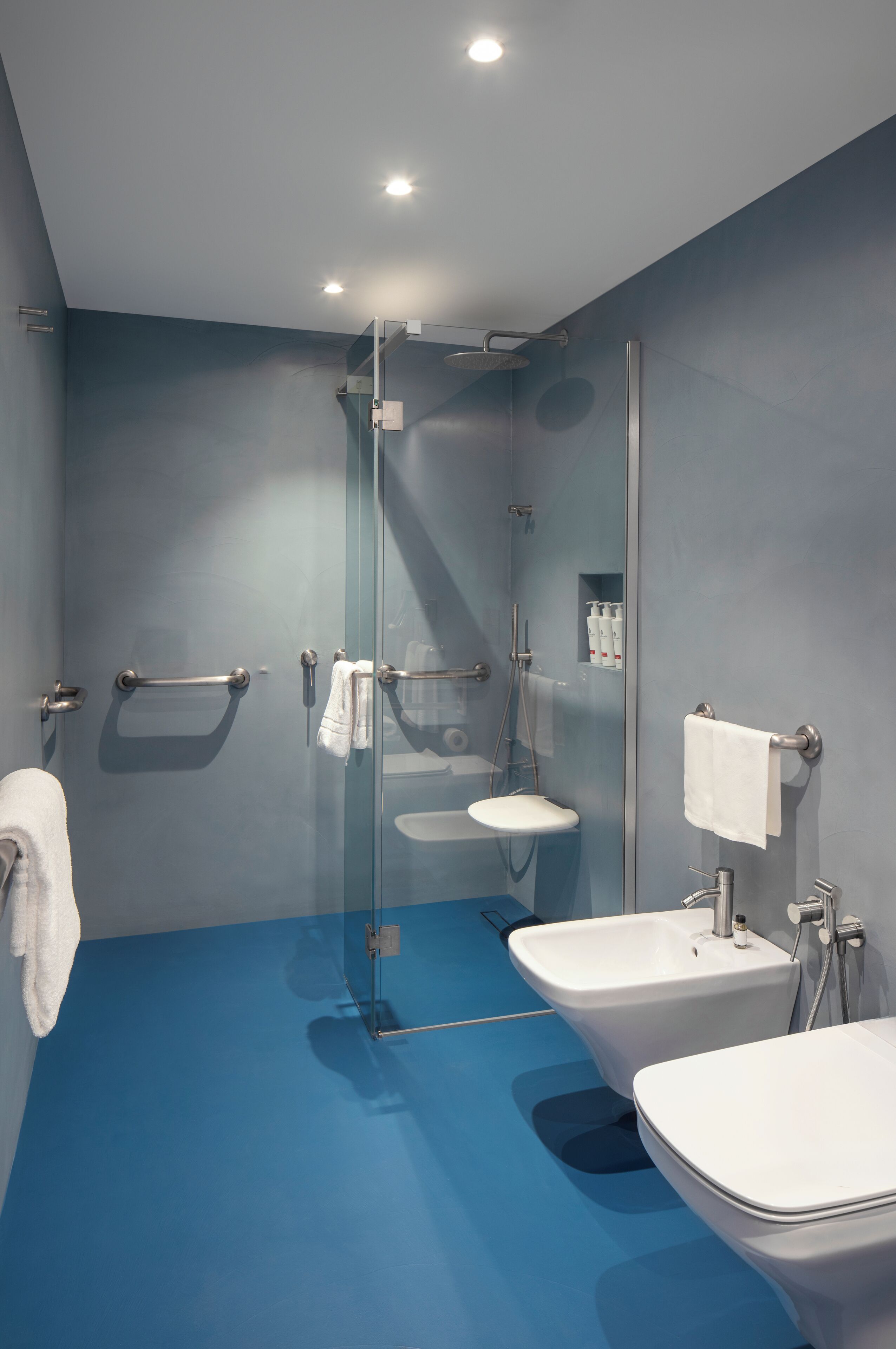 A modern bathroom with a glass shower enclosure, two sinks, and a glass door.