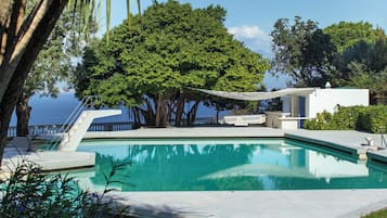 Una piscina al aire libre de temporada, sombrillas, tumbonas