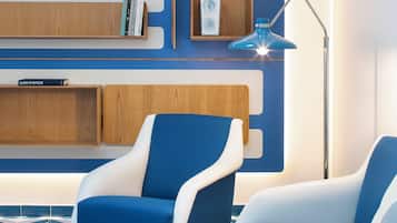 Ein modernes Wohnzimmer mit blauer und weißer Einrichtung, einem geometrisch gemusterten Boden und eingebauten Holzbögen mit Büchern.