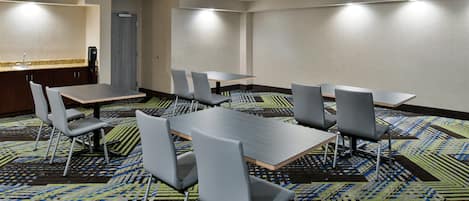 A conference room with a long table, six chairs, and a carpeted floor.