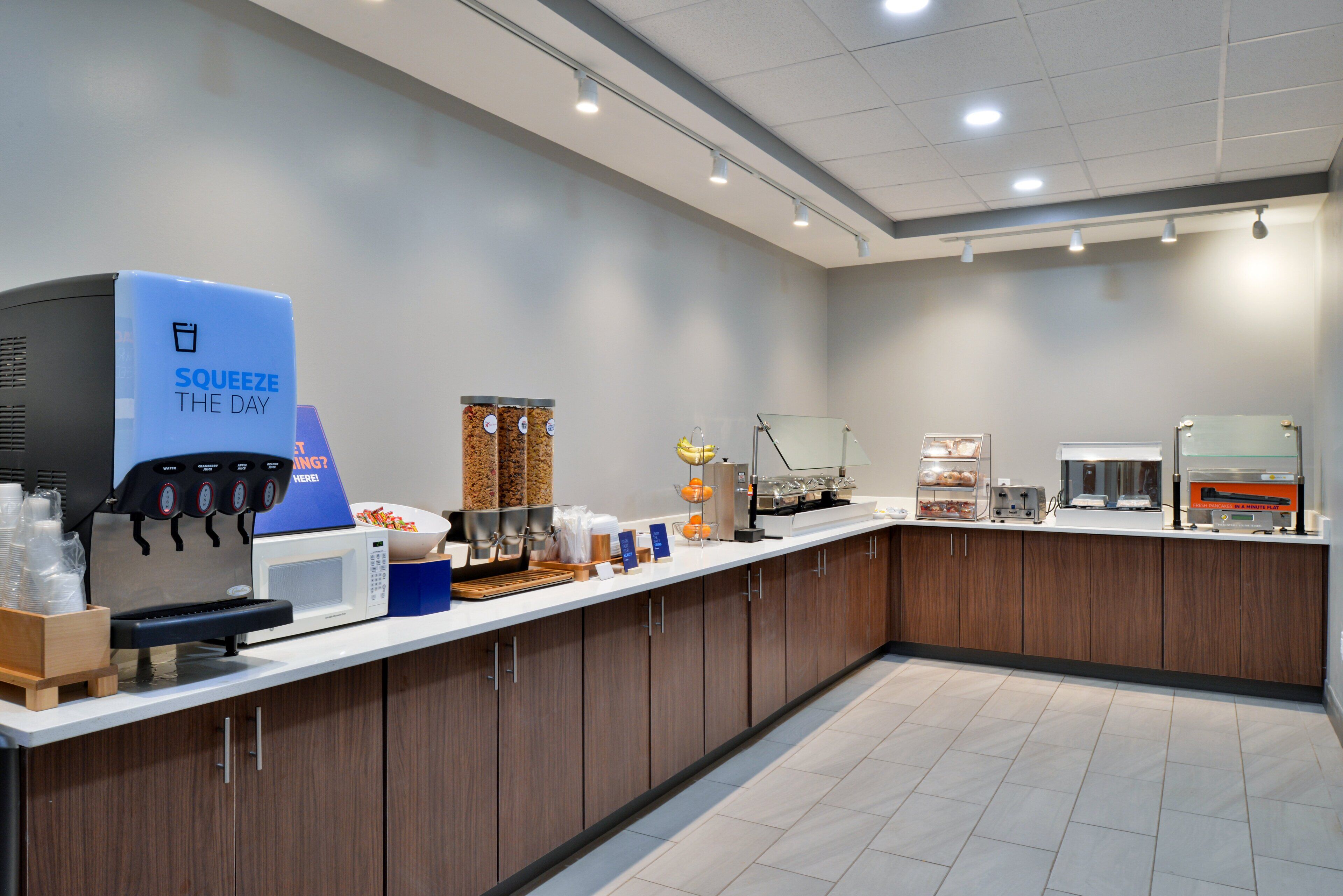 Uma estação de café moderna, com uma máquina de café da marca, diversas opções de café e um ambiente limpo e bem iluminado.