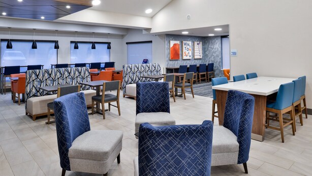 A modern hotel lobby with seating areas, tables, and a large conference table. - Holiday Inn Express Winston-Salem Medical Center Area by IHG (Winston-Salem)