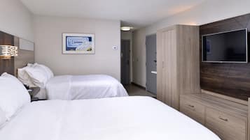 A hotel room with two beds, a TV, a wardrobe, and a painting on the wall.