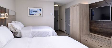 Una habitación de hotel con dos camas, un televisor, un armario y un cuadro en la pared.