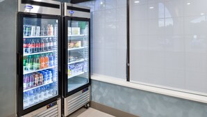 Two refrigerated beverage dispensers in a commercial setting with a window and a tiled wall. - Holiday Inn Express Winston-Salem Medical Center Area by IHG (Winston-Salem)