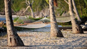 A hammock tied between two trees on a sandy beach. - Small Hope Bay Lodge  (Andros Town)