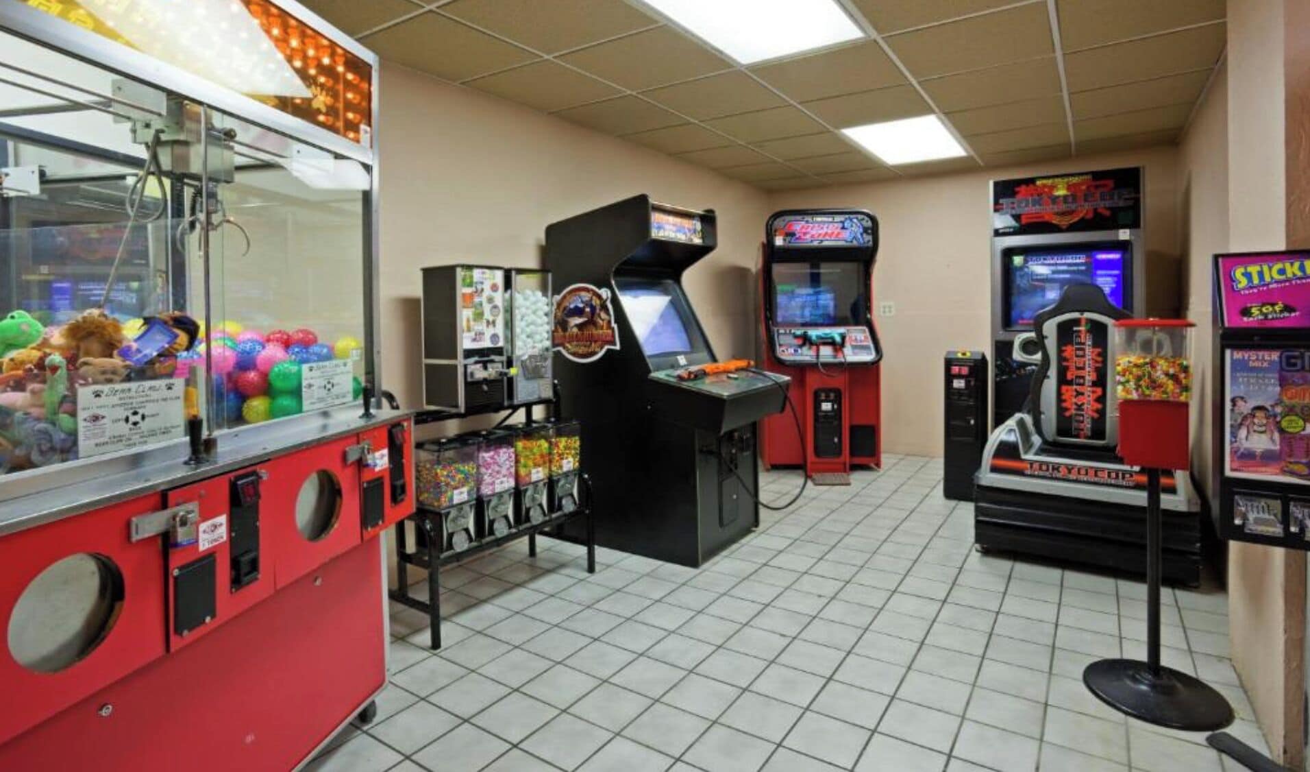 Una sala de juegos con diversas máquinas, incluyendo máquinas de garra y juegos de carreras.