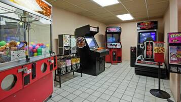 Una sala de juegos con diversas máquinas, incluyendo máquinas de garra y juegos de carreras.