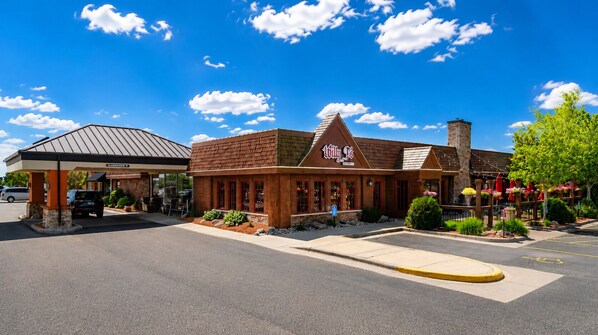 A building with a gas station on the left, a restaurant with a red awning, and a brick chimney.