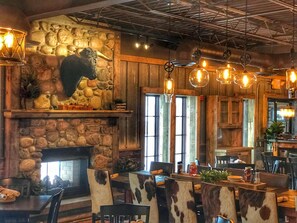 A rustic interior with stone walls, a fireplace, and cowhide chairs. - Alexandria Hotel & Conference Center (Alexandria)