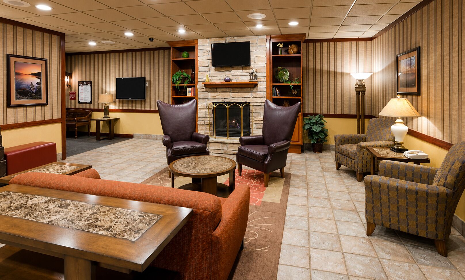 Un vestíbulo de hotel con sillones de cuero, chimenea, televisor y zona de comedor.