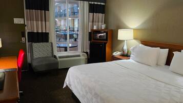 Ein Hotelzimmer mit Bett, Schreibtisch, Stuhl, Fernseher, Heizung und einem Fenster mit Vorhängen.