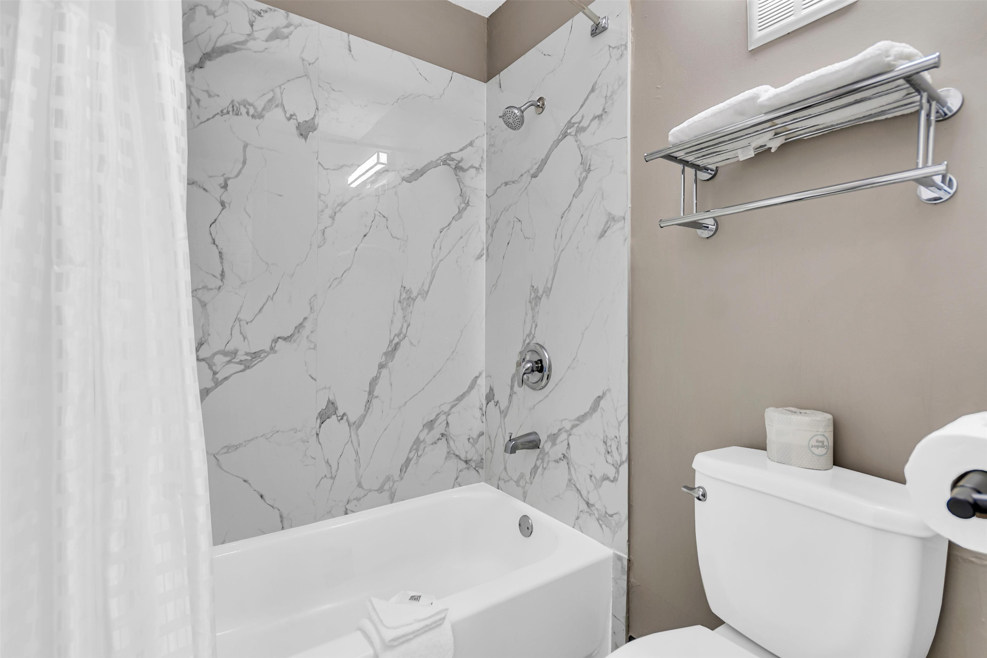 A bathroom with a bathtub, a shower, a toilet, and a towel rack.