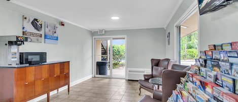 A reception area with a wooden cabinet, a microwave, a bulletin board with brochures, and a view of the outdoors.