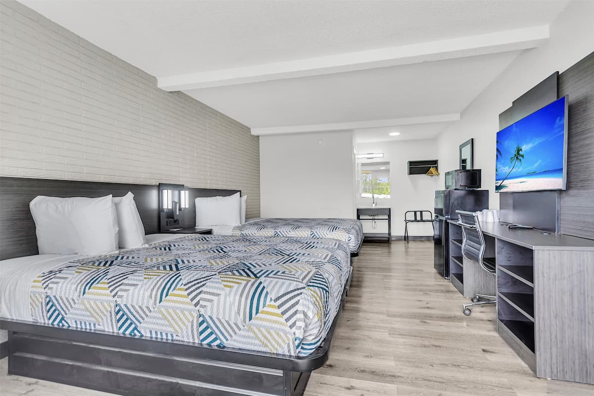 A modern hotel room with a large bed, a desk, and a television.