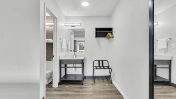 Un baño moderno con lavamanos, espejo y toallero blancos.