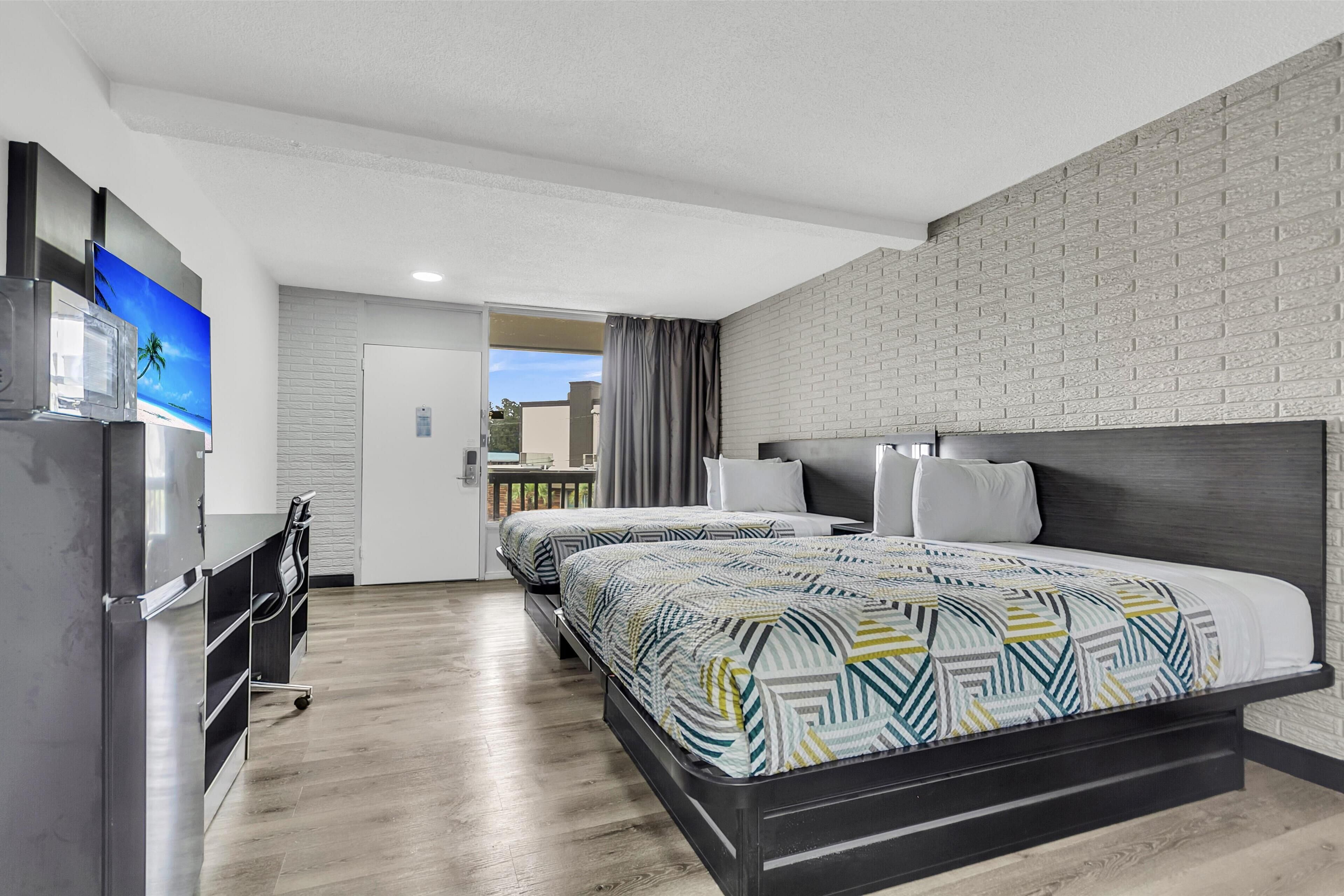 Una habitación de hotel moderna con dos camas, un escritorio y vistas al exterior.