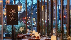 A restaurant with a glass ceiling, tables set with tableware, and a sign with a butterfly design. - M Social Hotel Paris (Paris)