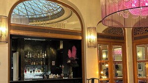 A bar area with a glass ceiling, plush seating, and a checkered floor. - M Social Hotel Paris (Paris)