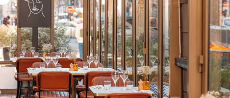 An outdoor restaurant with tables set for dining, featuring a view of the street and trees.