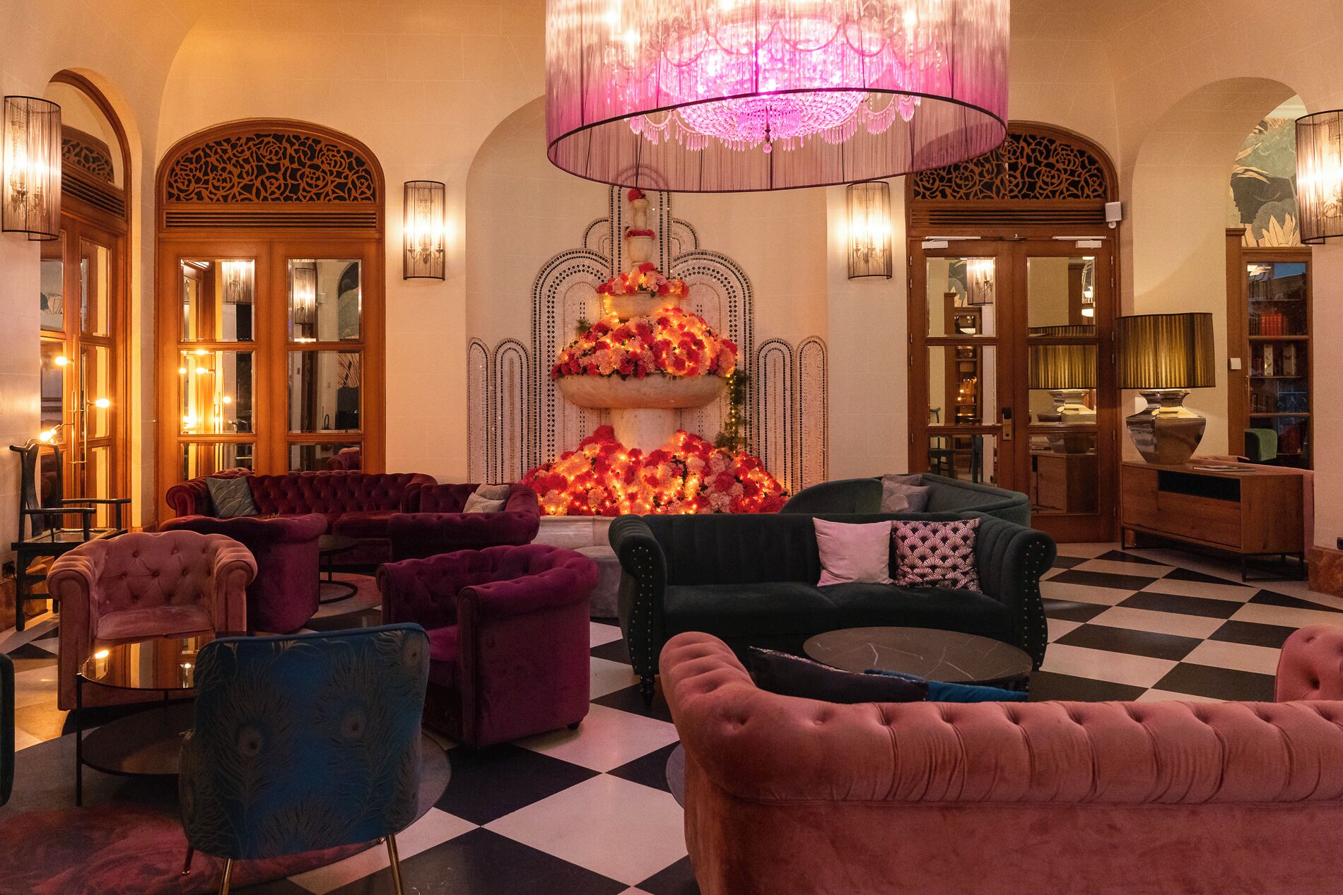 A luxurious lobby with plush seating, ornate decor, and a central floral arrangement.
