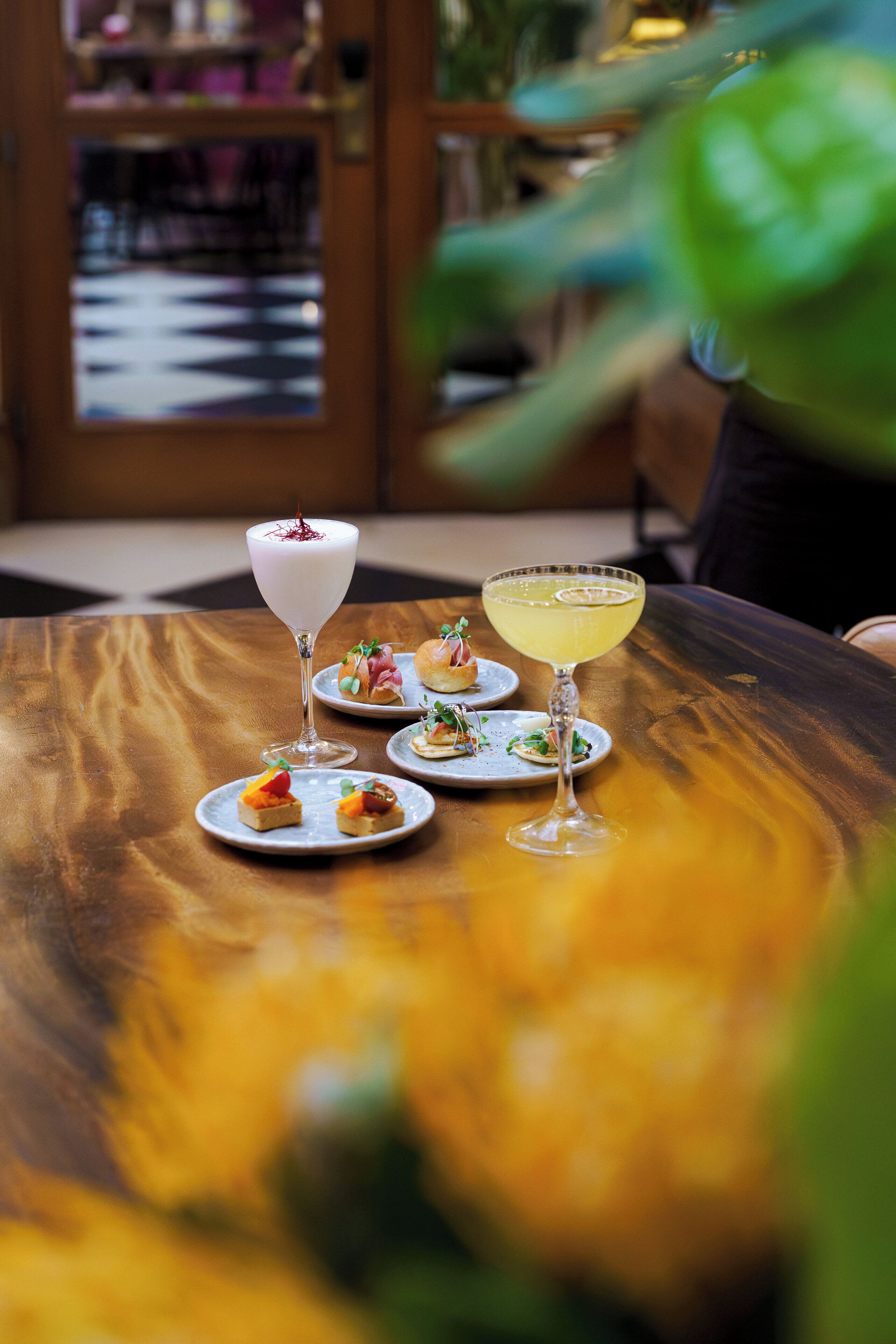 A table with three drinks and small plates of food.