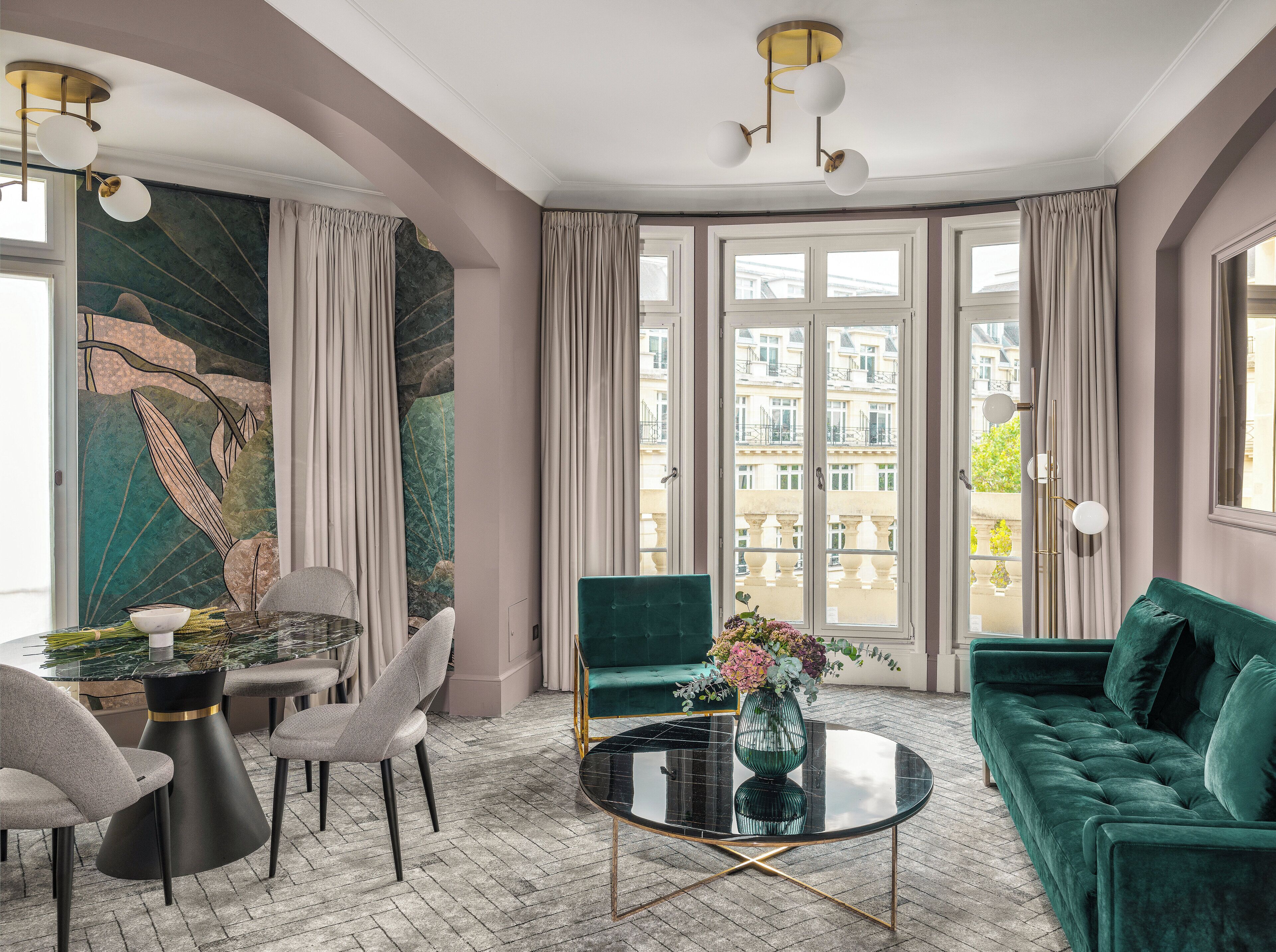 A modern living room with a green sofa, a round coffee table, and a dining area with chairs and a table.