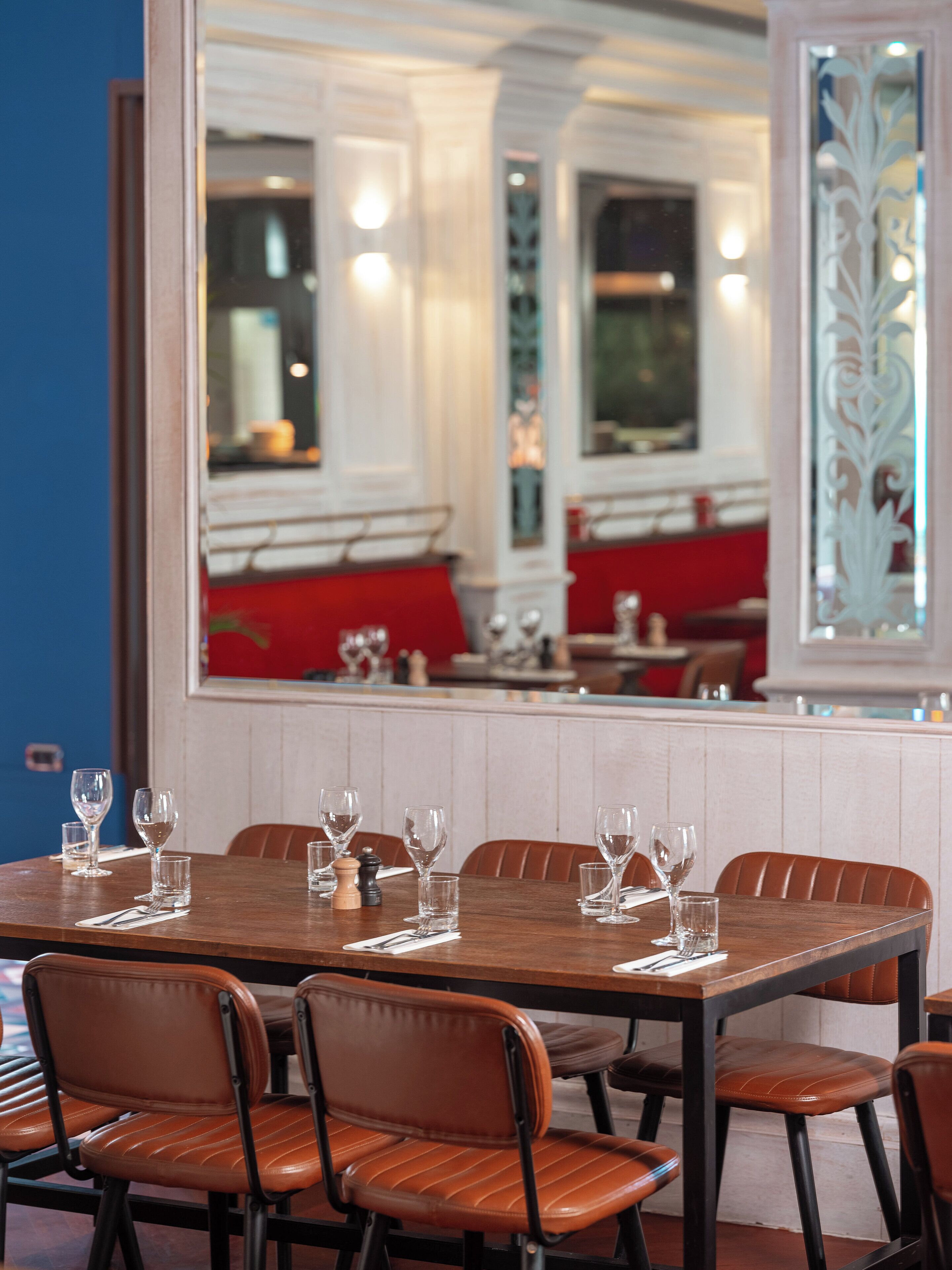 Un coin repas avec une table en bois dressée pour six personnes, entourée de fauteuils en cuir.