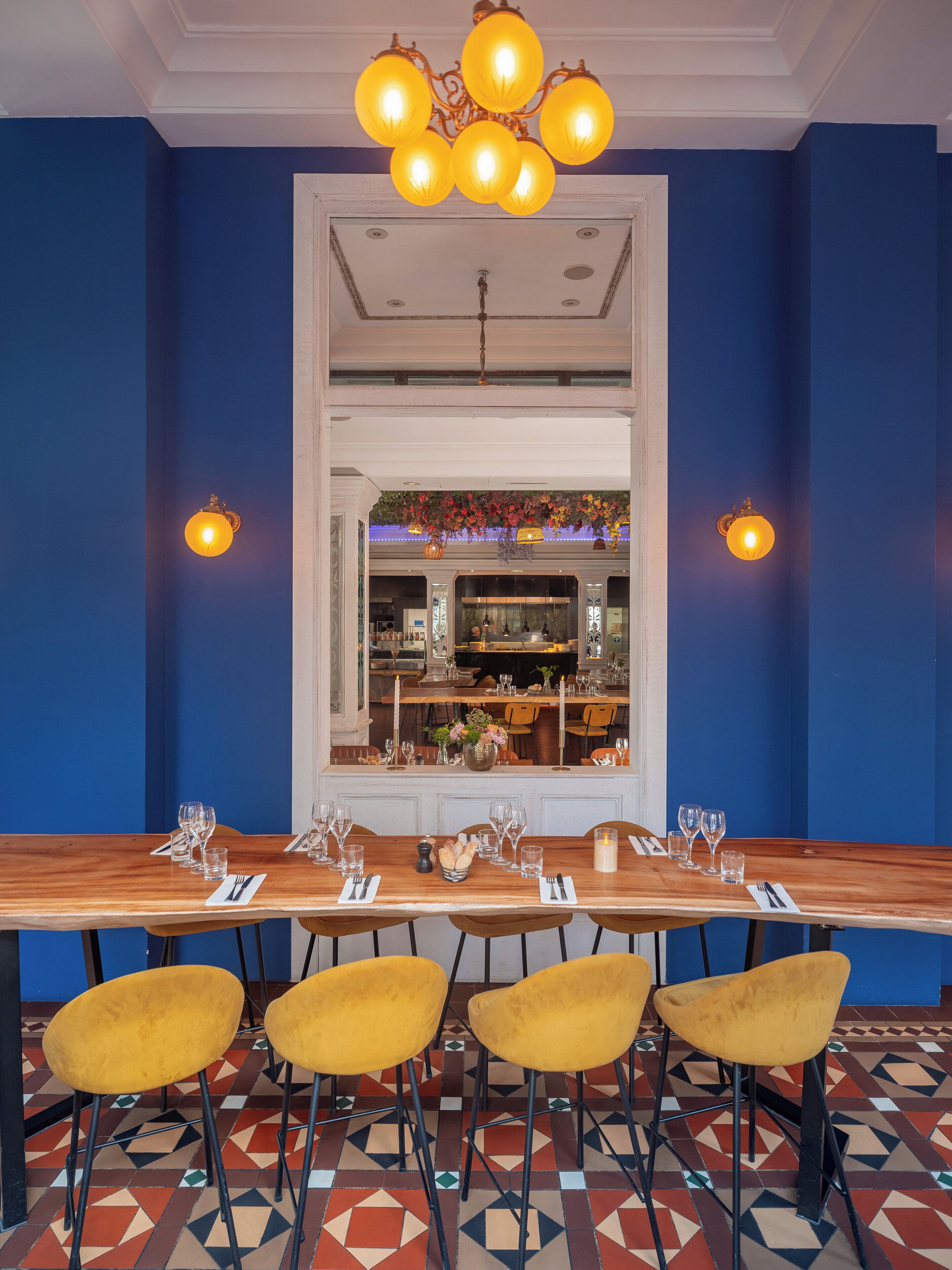 A dining area with a long wooden table, yellow chairs, and a patterned floor.