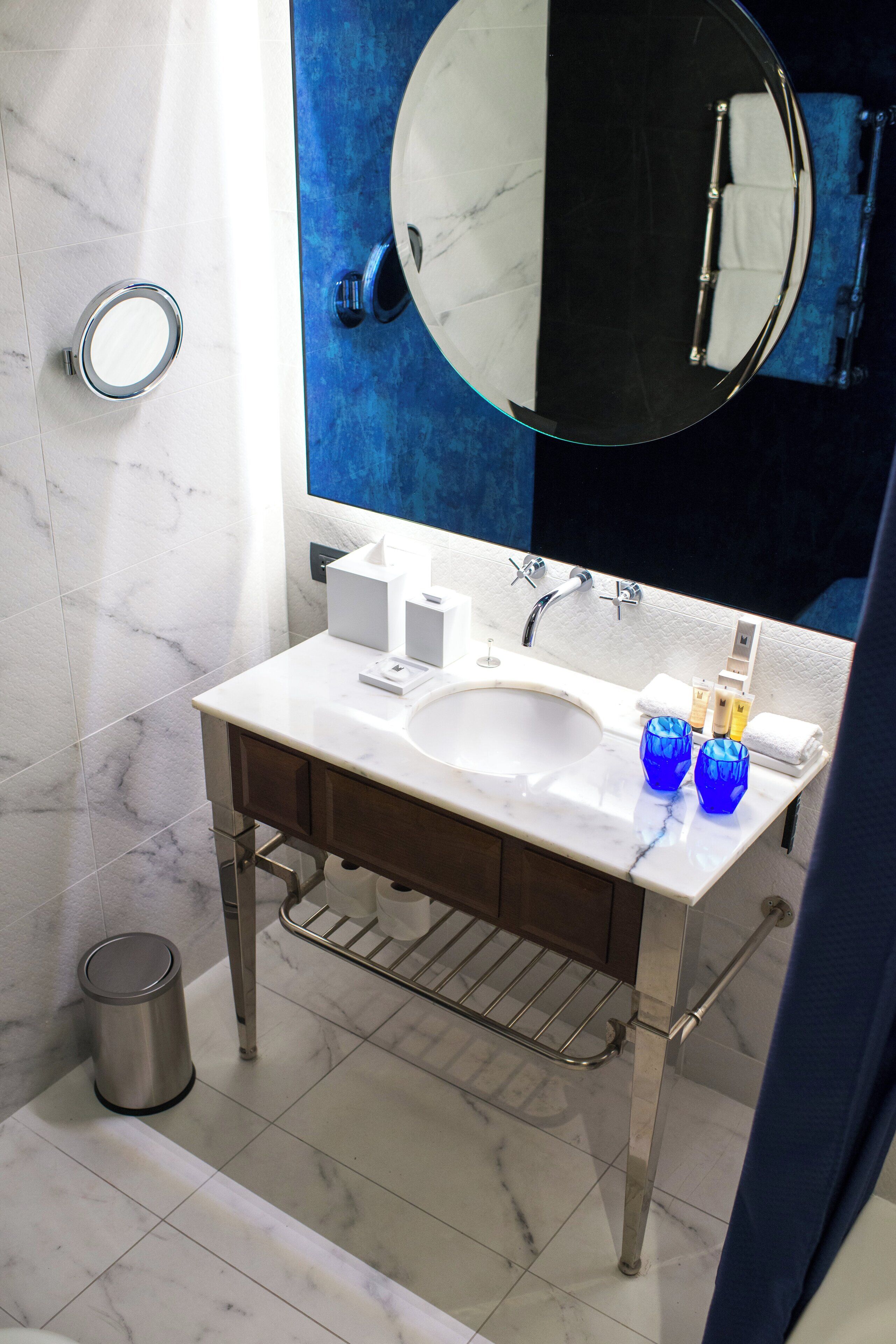 A bathroom with a marble sink, a large mirror, and a towel rack.
