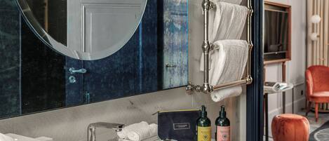 A bathroom with a large mirror, a white sink, and two bottles of shampoo.
