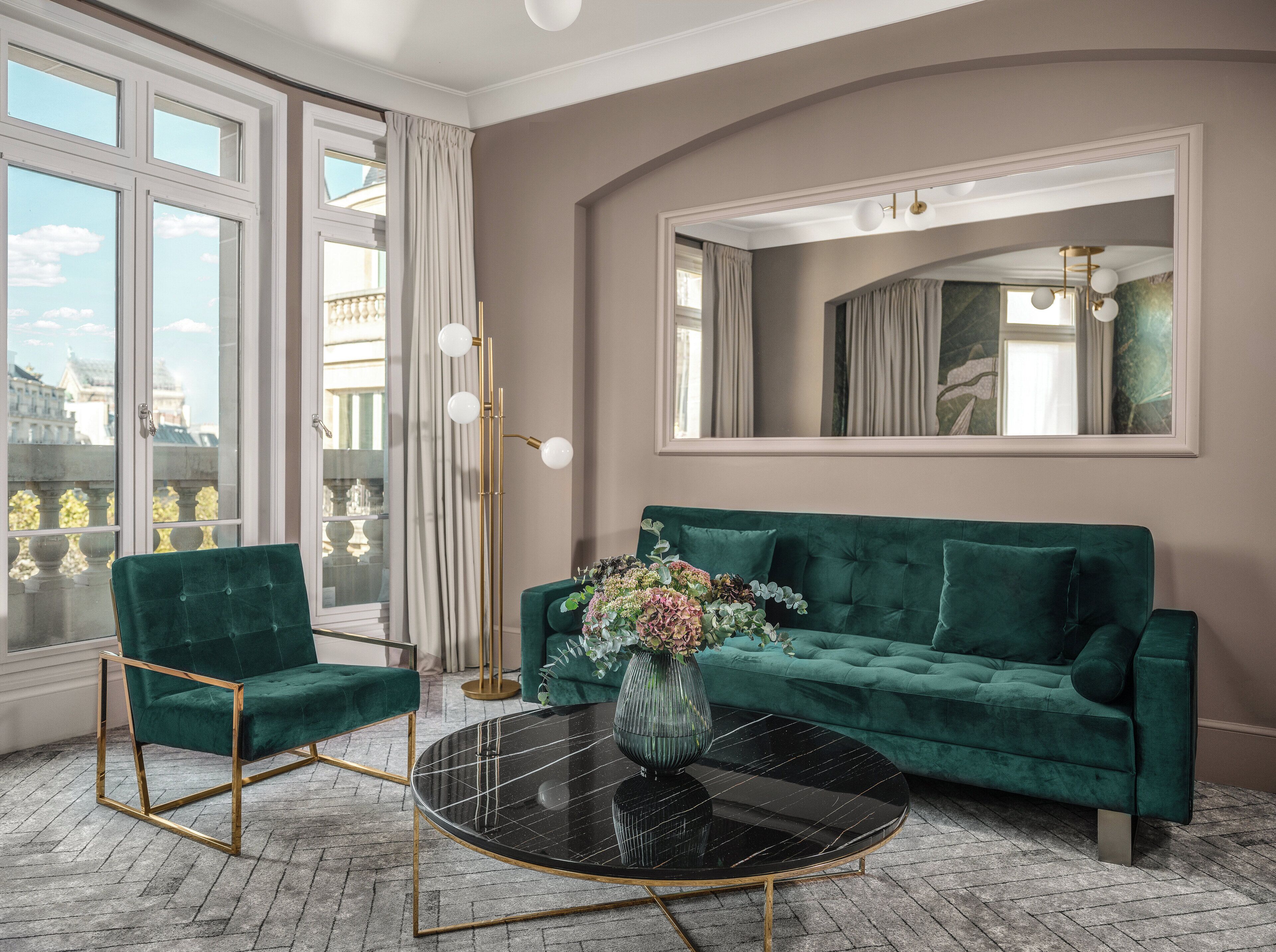 A living room with a green sofa, a round black table, and a tall floor lamp.