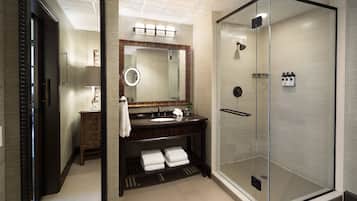 A modern bathroom with a glass-enclosed shower, a vanity with a mirror, and a towel rack.