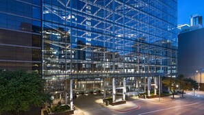 A modern glass building with a reflective facade, multiple entry points, and a landscaped courtyard. - Omni Austin Hotel (Austin)