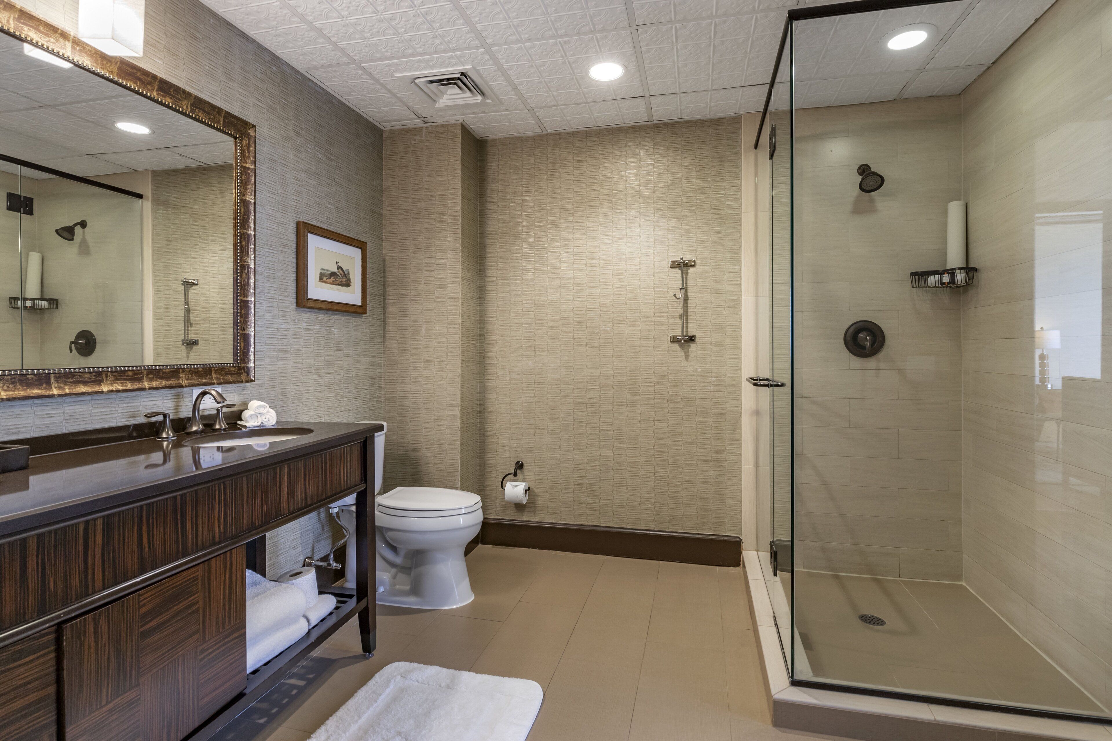 A modern bathroom with a glass-enclosed shower, a dark wood vanity, and a large mirror.