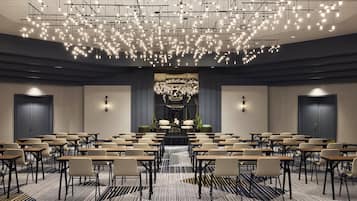 A conference room with rows of tables and chairs, a chandelier, and a large decorative piece in the center.