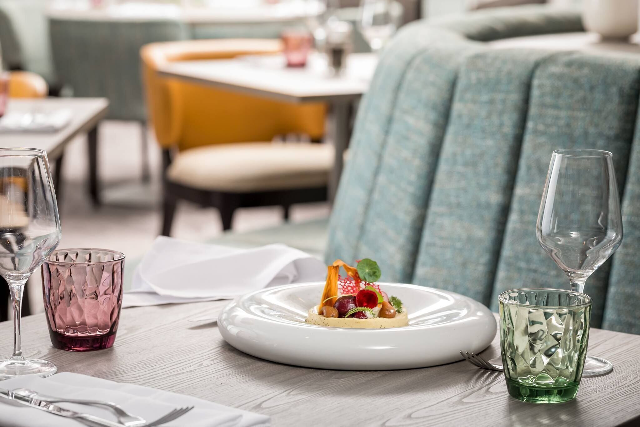 A dining table with a plate of food, two glasses, and cutlery.