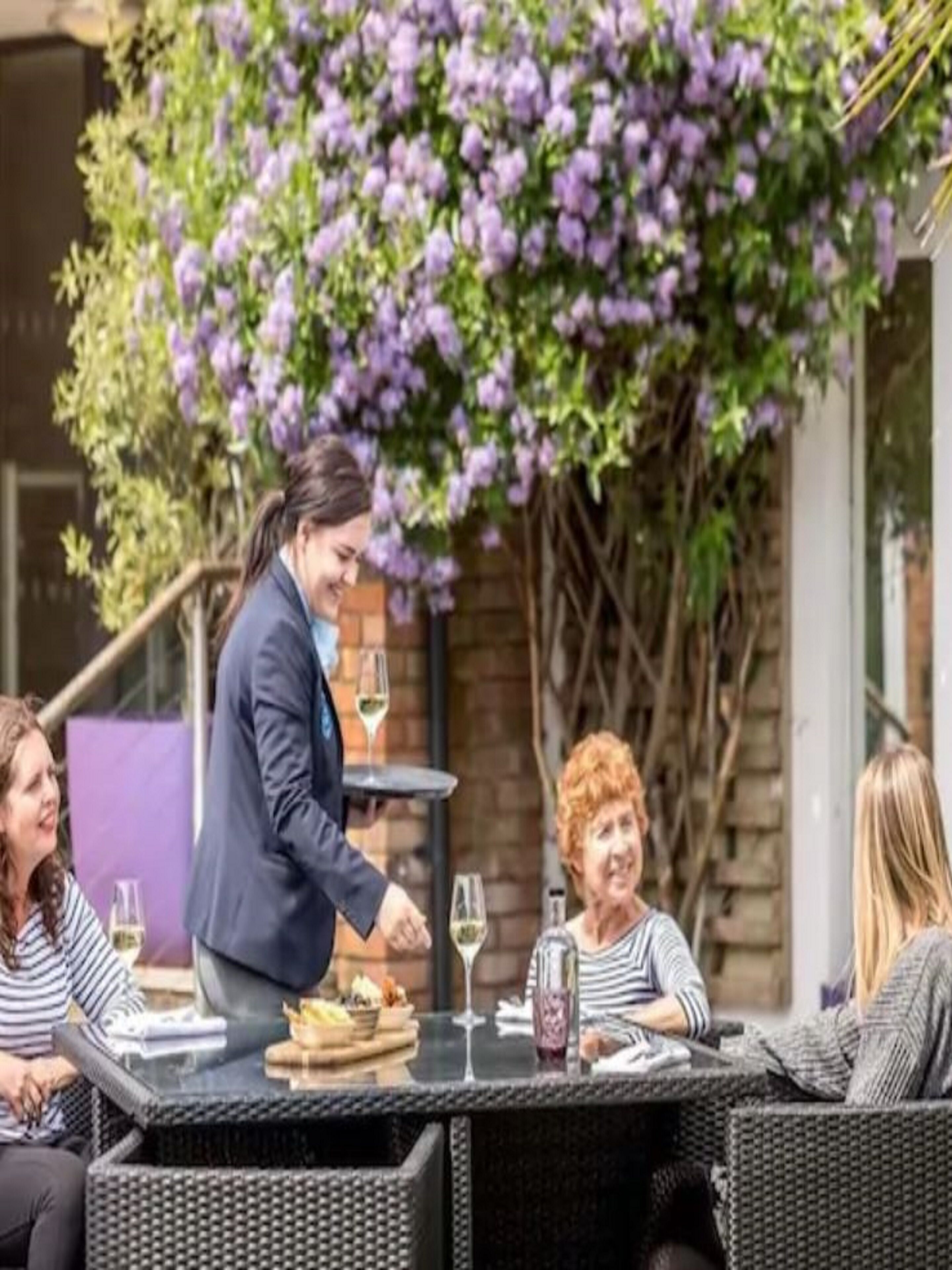 An outdoor dining area with wicker furniture and a table set for a meal.