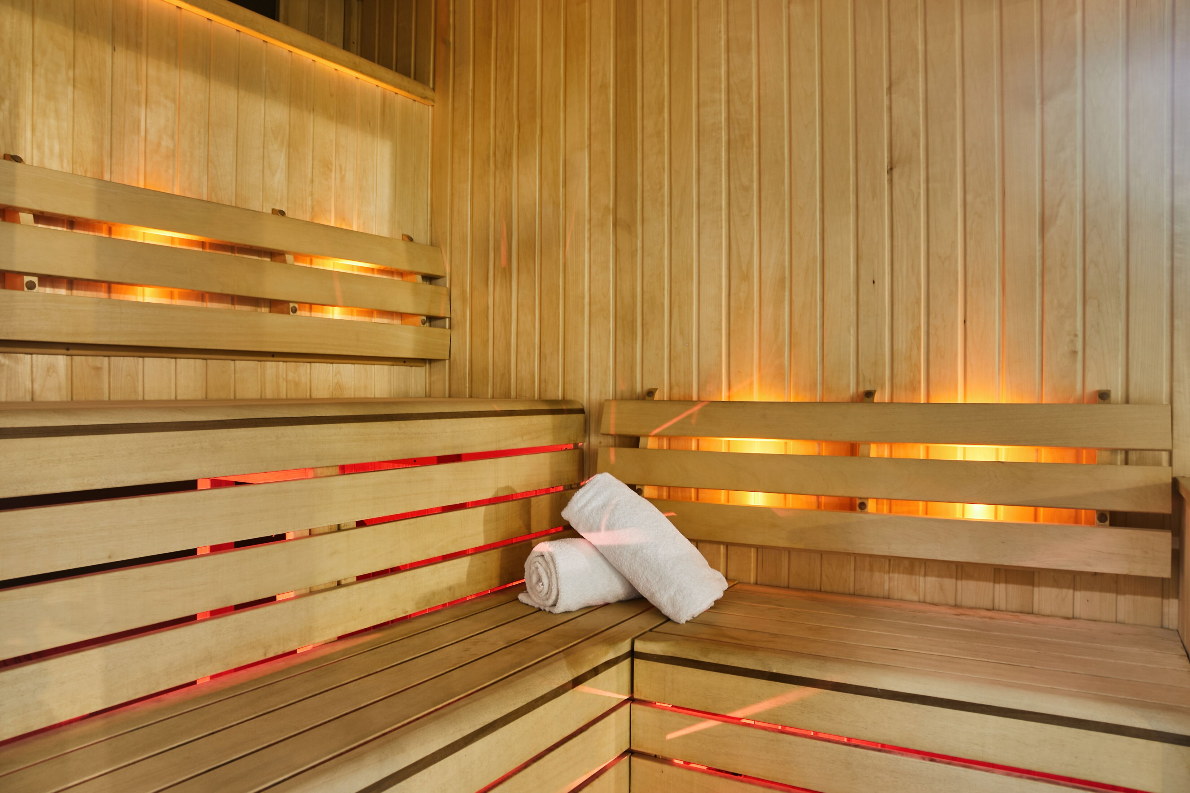 A sauna with wooden benches and red heating elements.