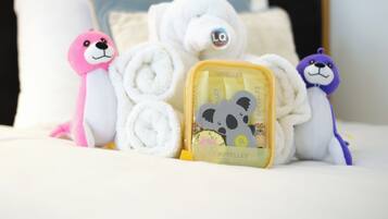 A bed with rolled towels, a plush toy, and a small box with a bear design.