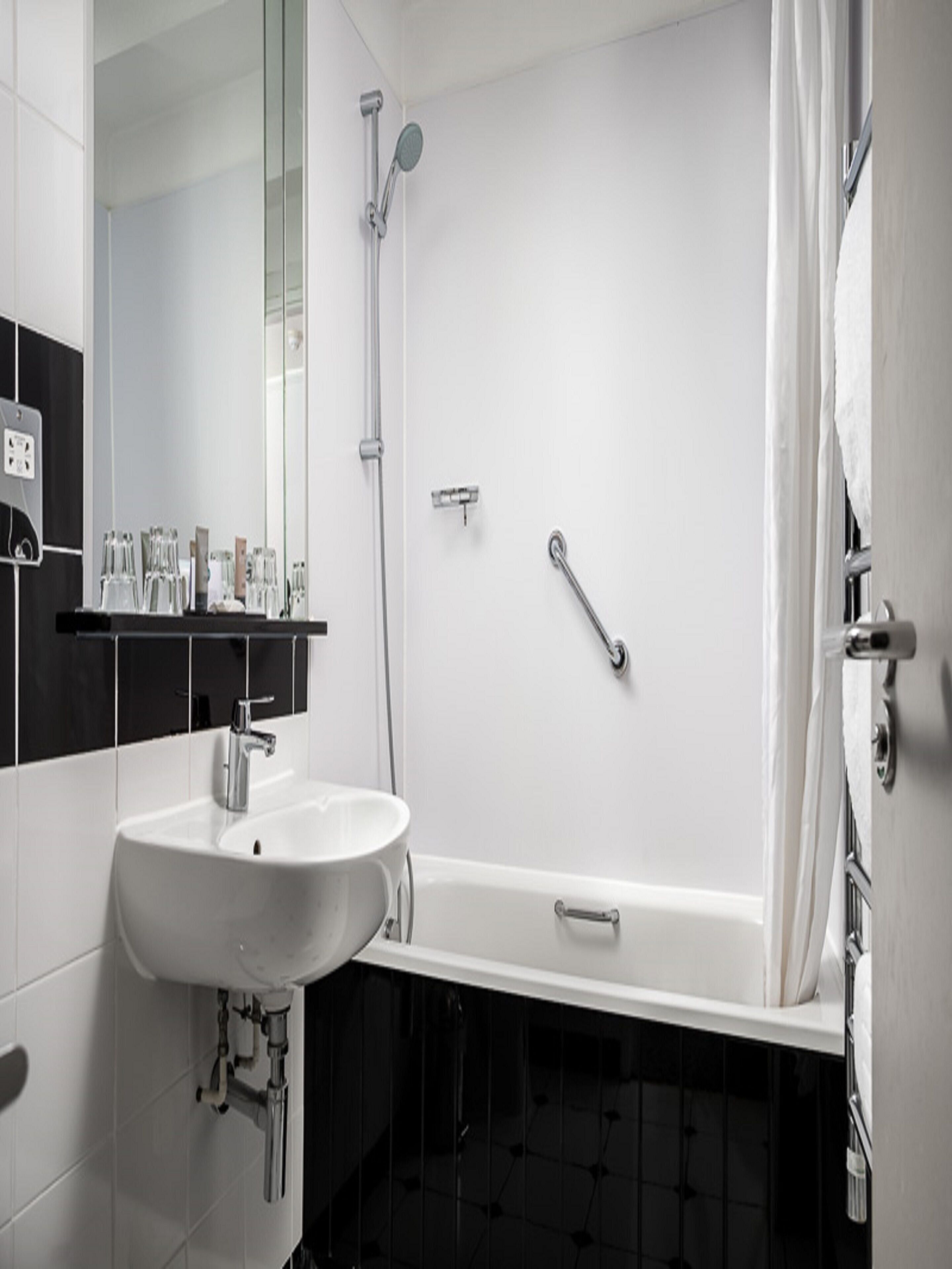 Een moderne badkamer met een witte wastafel, een bad en een douche.