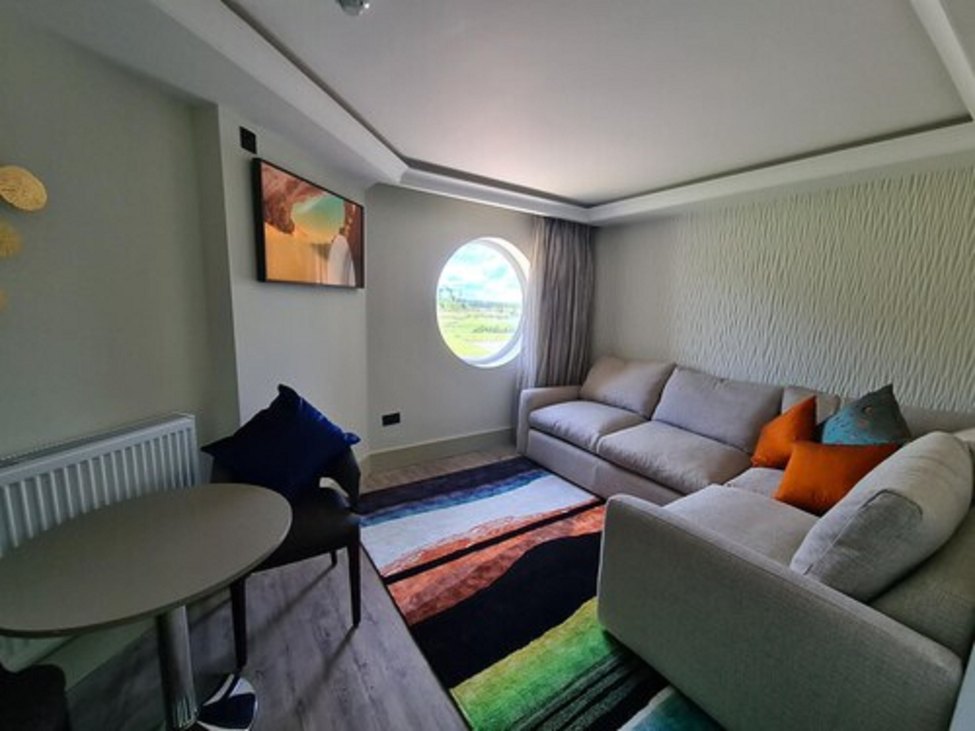Uma sala de estar moderna com um sofá, uma mesa pequena e uma janela com cortinas.