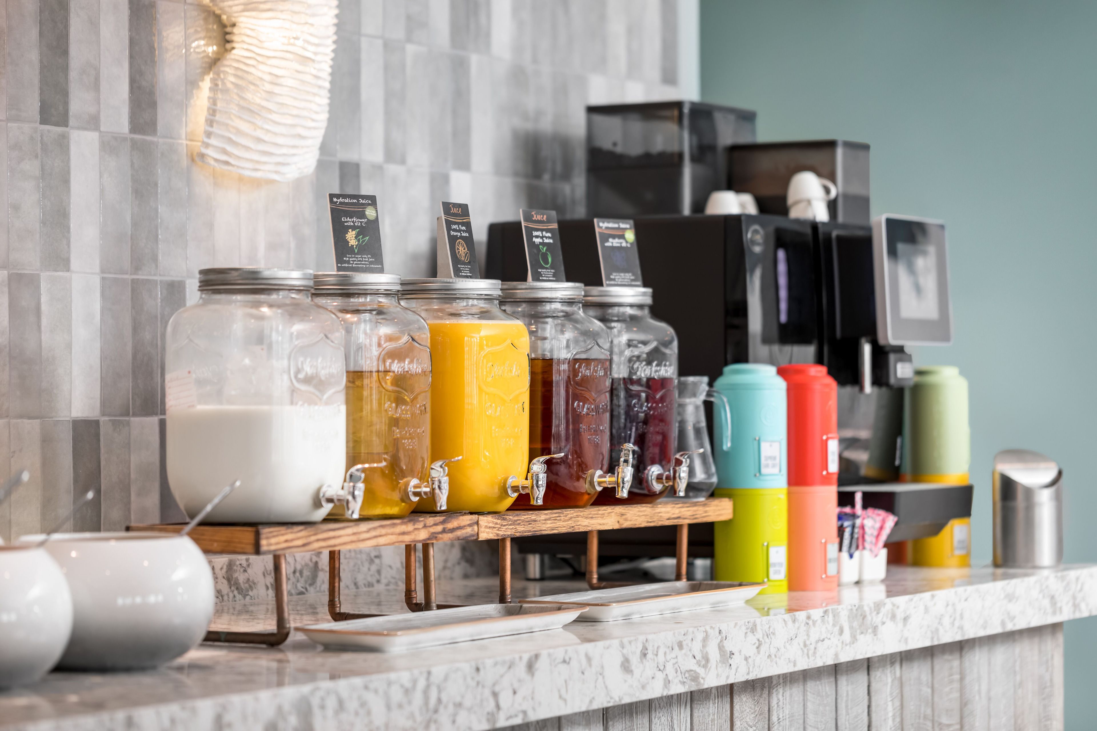 A beverage station with multiple dispensers and a coffee machine in the background.