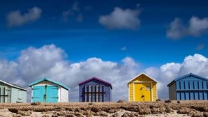 Five beach huts in various colors against a clear sky. - The Langstone Quays (Hayling Island)