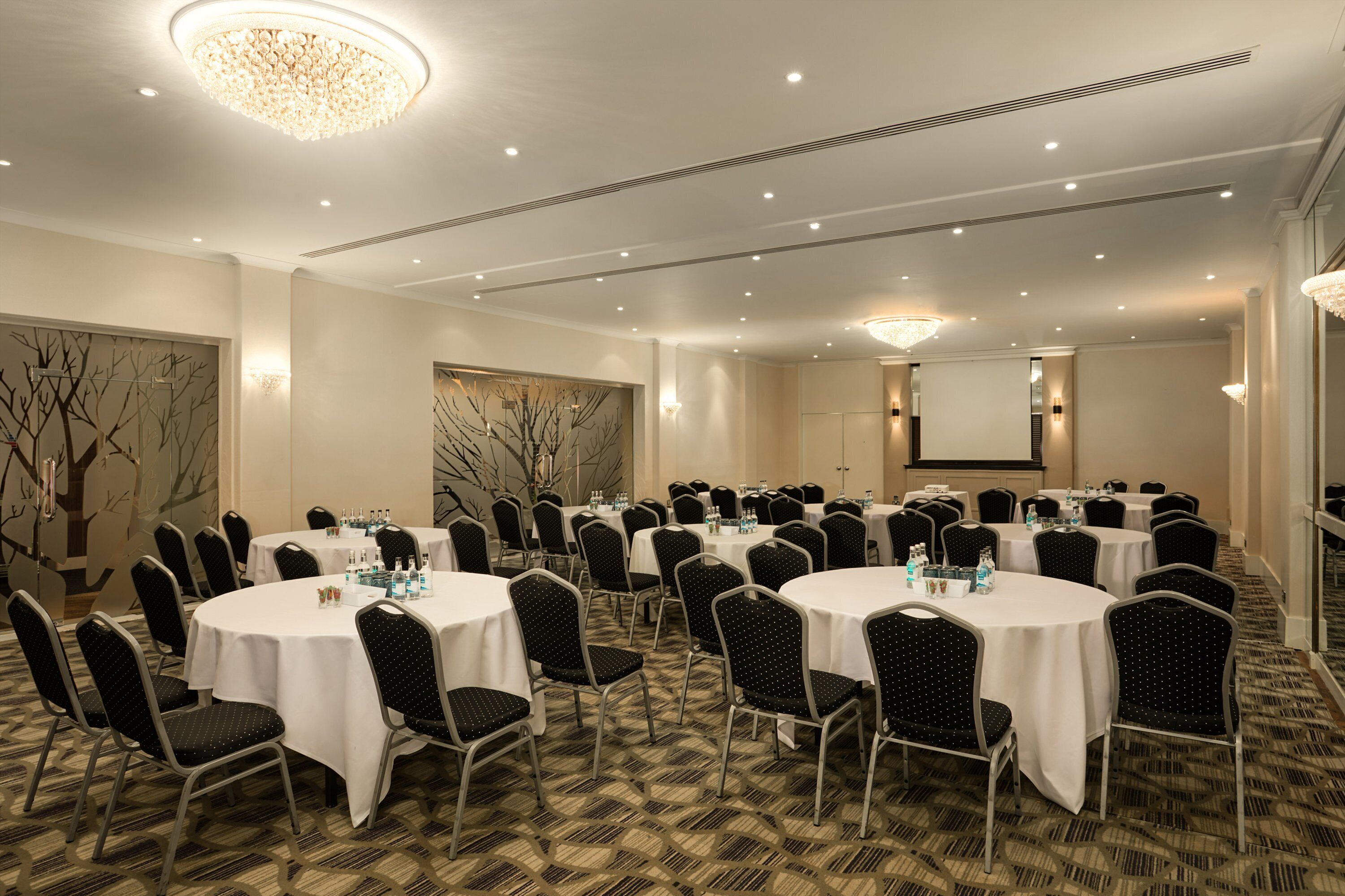A conference room with round tables and chairs, equipped with water bottles and nameplates.