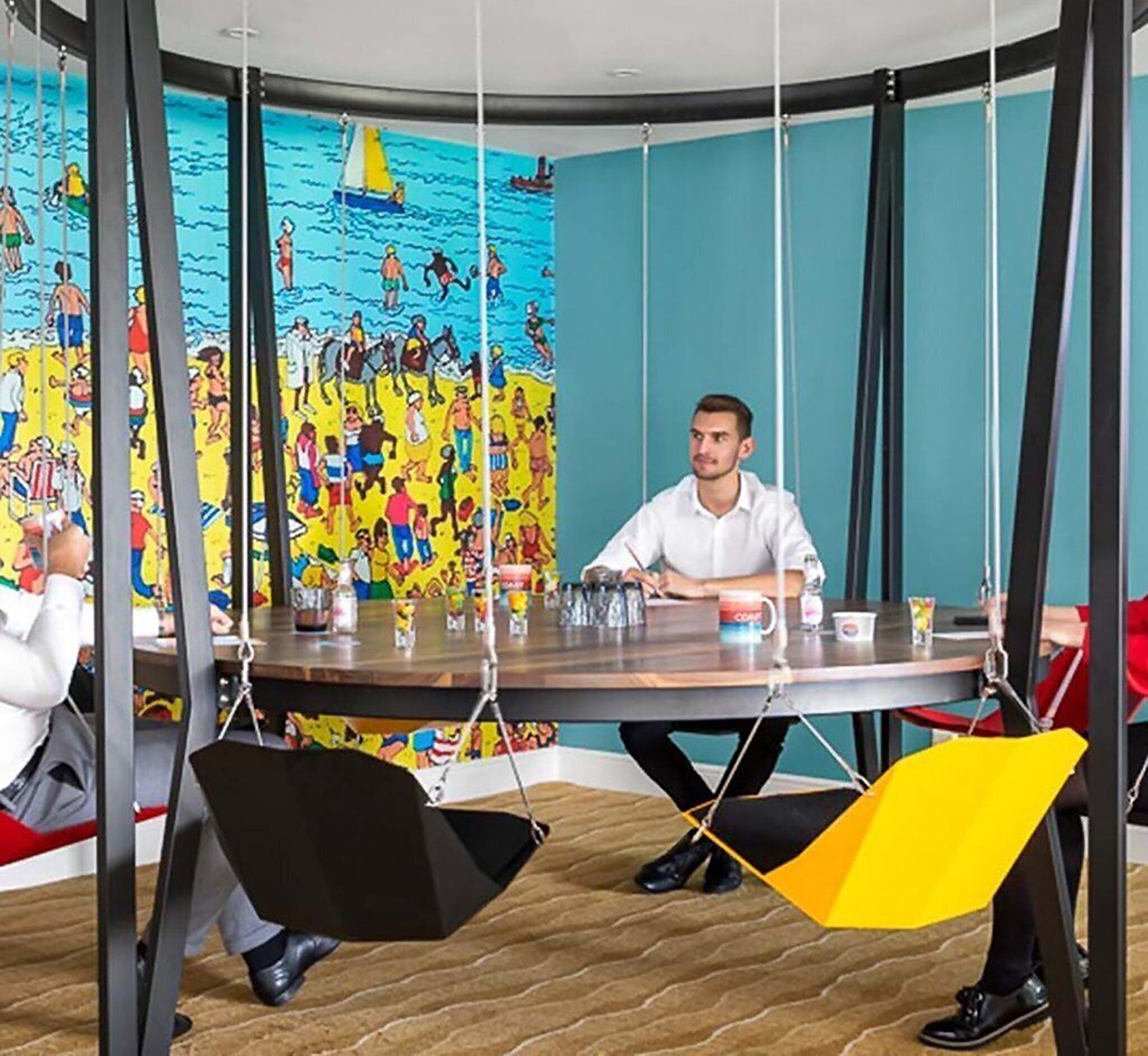 A conference room with a round table, chairs, and a colorful mural on the wall.