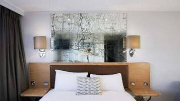Una habitación de hotel con una cama grande, dos mesitas de noche y un mapa colgado en la pared.